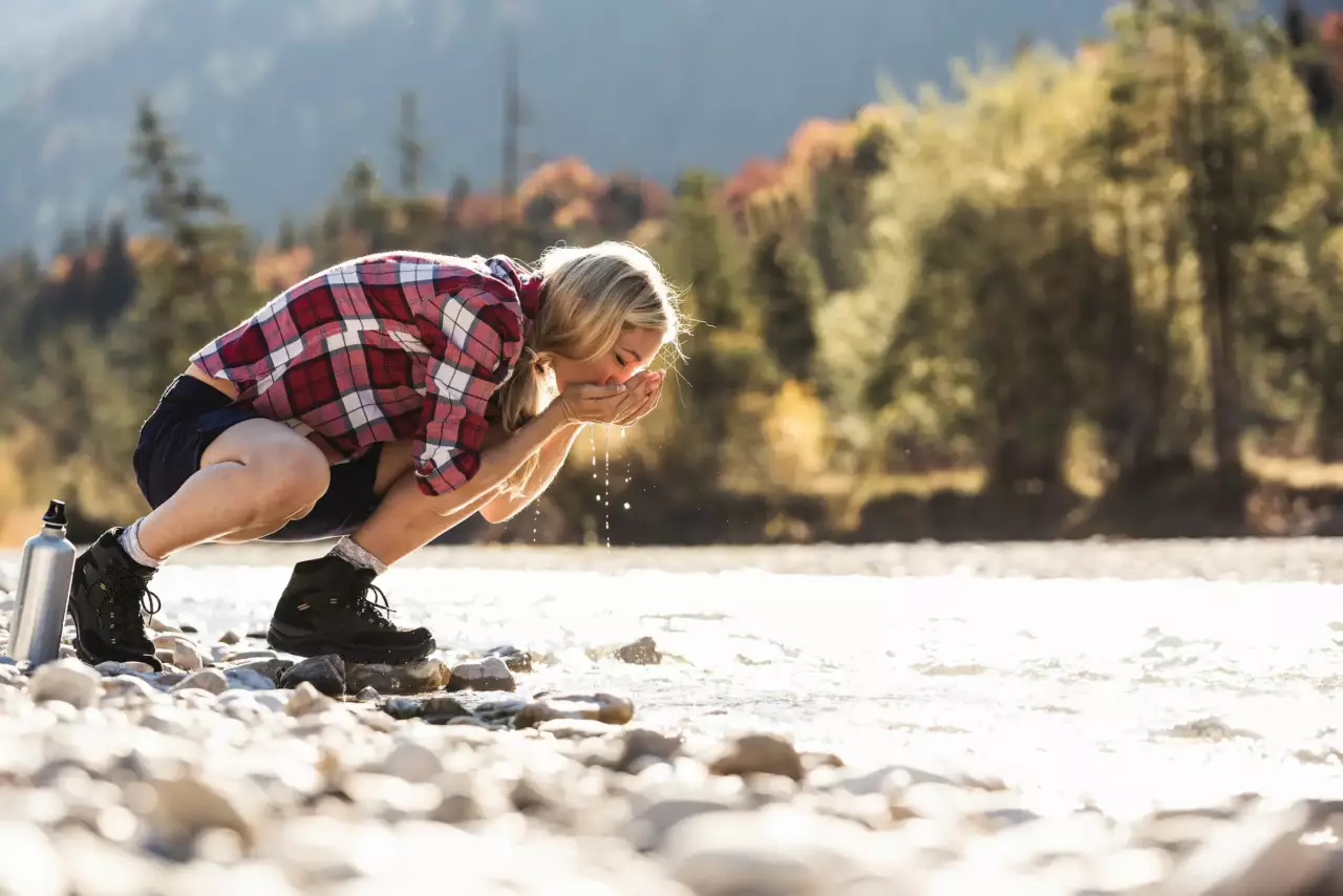 Hiker drinking from a mountain lake in autumn – summer holiday in Ramsau am Dachstein