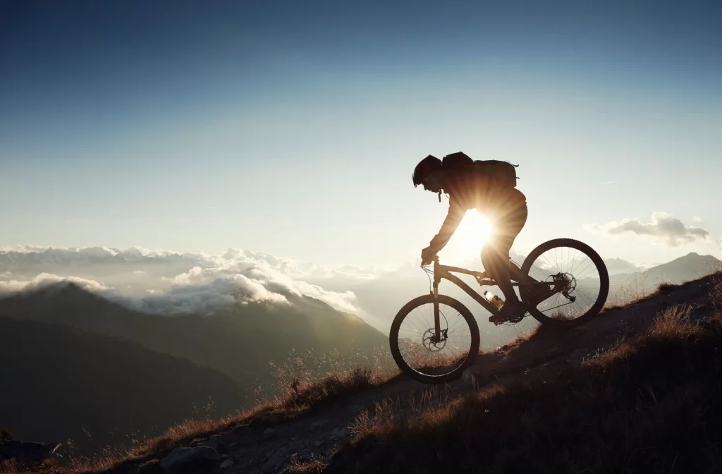 Cyklista na horském kole v protisvětle na horské stezce – aktuality z Ramsau am Dachstein